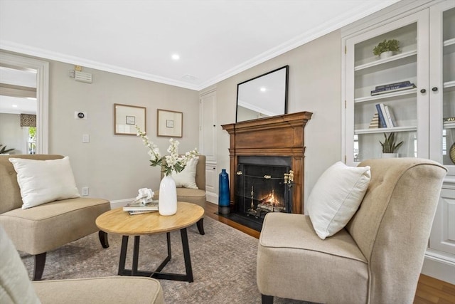 sitting room with hardwood / wood-style floors, built in shelves, and crown molding