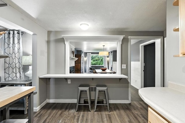 149 N Main St, South Hadley, MA 01075 - kitchen featuring dark wood-type flooring, a textured ceiling, a breakfast bar, and light countertops