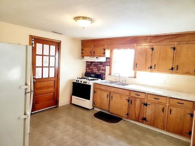 kitchen featuring a textured ceiling, white appliances, and sink