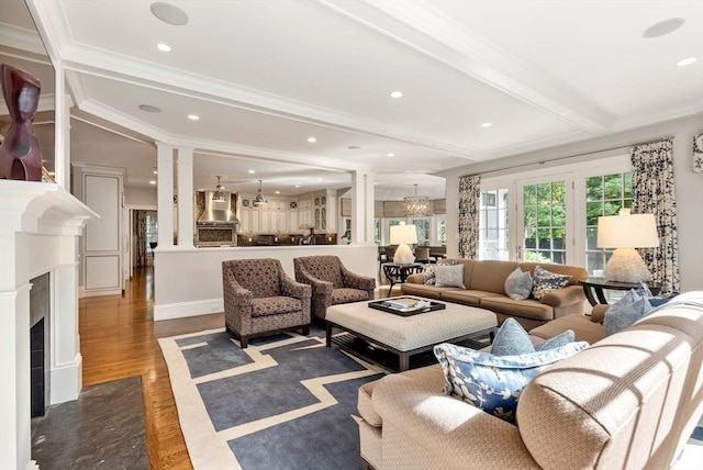 living area featuring dark wood-style floors, beam ceiling, recessed lighting, a chandelier, and ornate columns