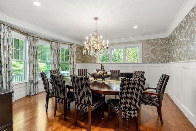 dining area with wallpapered walls, wood finished floors, crown molding, and a wainscoted wall