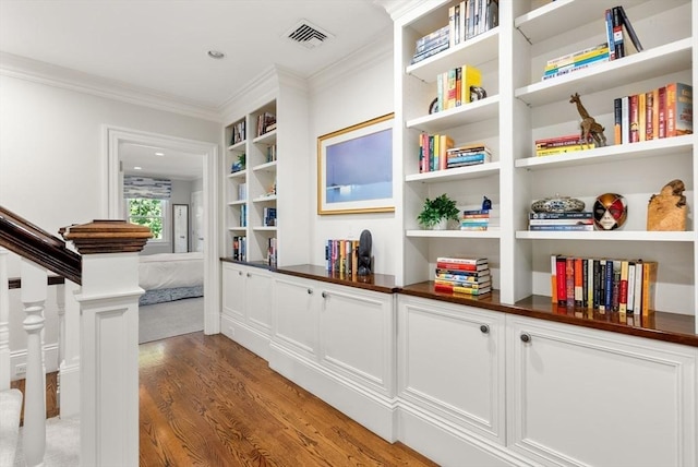 details featuring ornamental molding, visible vents, built in features, and wood finished floors