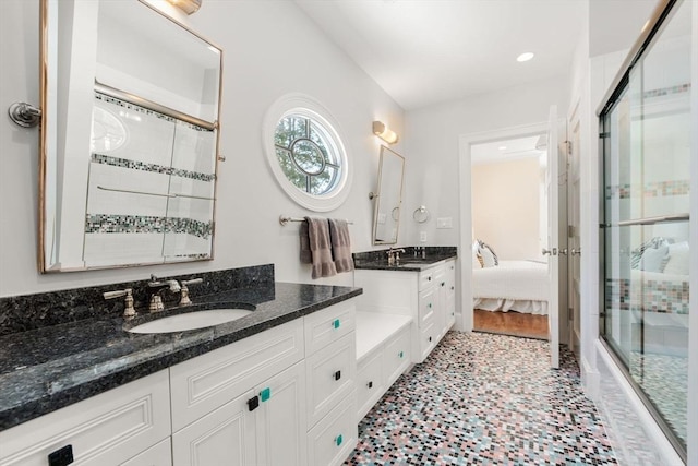 full bath featuring two vanities, tiled shower, a sink, and ensuite bathroom