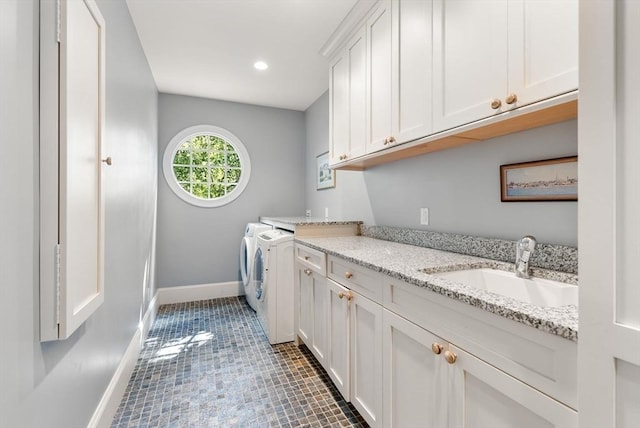 washroom with cabinet space, baseboards, washing machine and clothes dryer, a sink, and recessed lighting