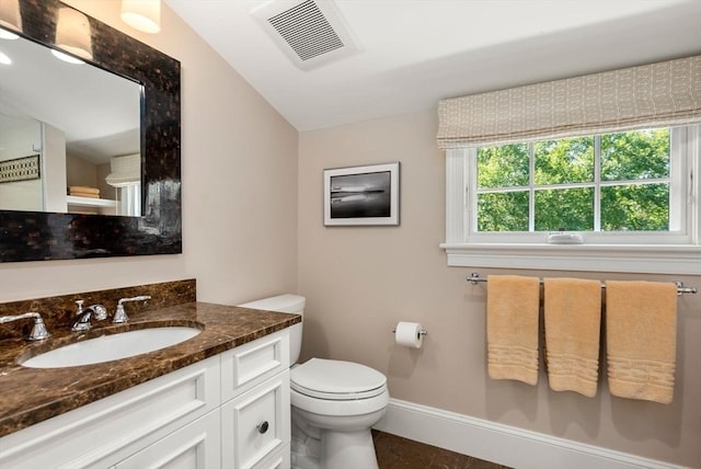 bathroom featuring toilet, vanity, visible vents, and baseboards