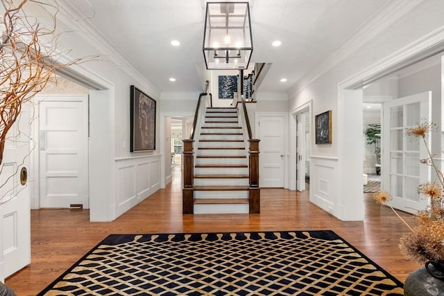 entrance foyer featuring ornamental molding, wood finished floors, and a decorative wall