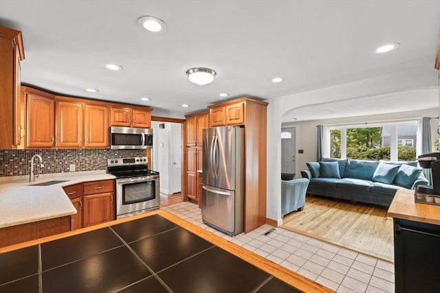 kitchen featuring light tile patterned flooring, arched walkways, open floor plan, light countertops, and appliances with stainless steel finishes