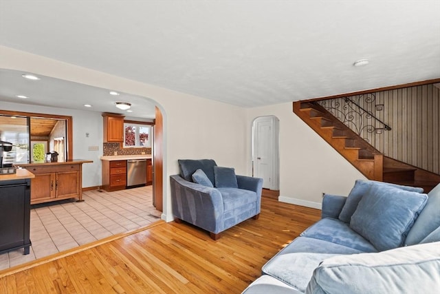 living room featuring recessed lighting, stairway, light wood finished floors, arched walkways, and baseboards