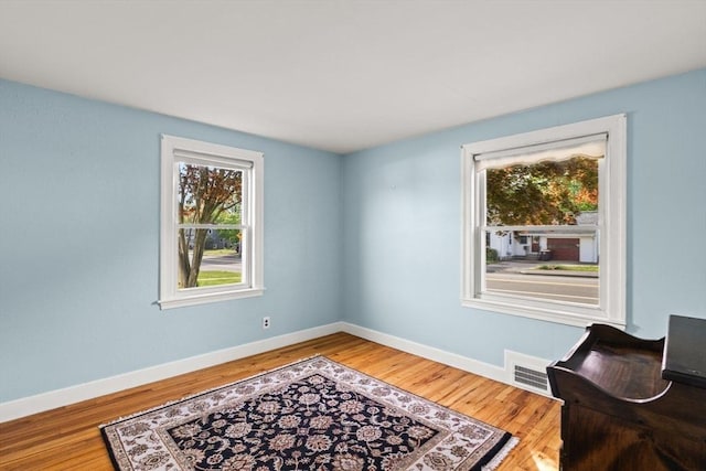 living area with visible vents, wood finished floors, and baseboards