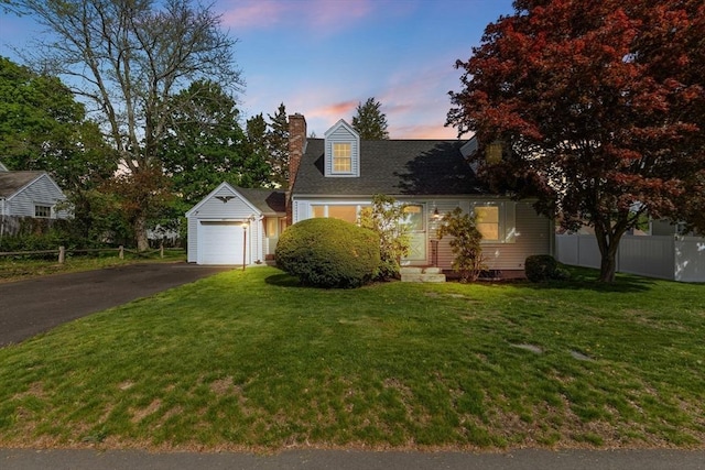 cape cod-style house featuring a chimney, a front yard, aphalt driveway, and fence