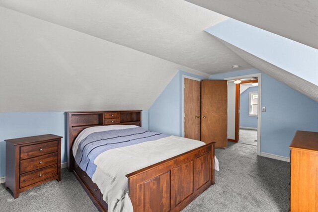 carpeted bedroom with lofted ceiling and baseboards