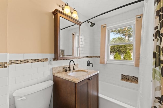 bathroom with tile walls, toilet, a wainscoted wall, vanity, and shower / tub combo with curtain