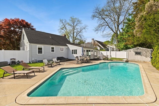 view of pool featuring an outbuilding, a diving board, a fenced backyard, a patio area, and a fenced in pool