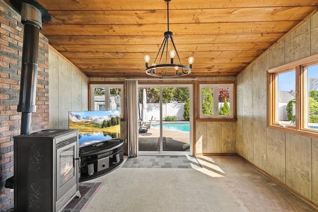sunroom / solarium with a notable chandelier and a wood stove