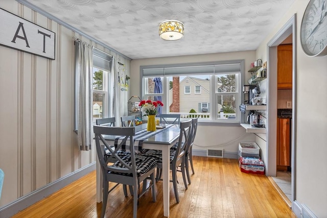 dining space featuring light wood finished floors, baseboards, and plenty of natural light