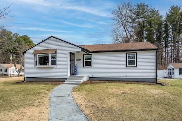 bungalow-style home featuring a front yard and roof with shingles