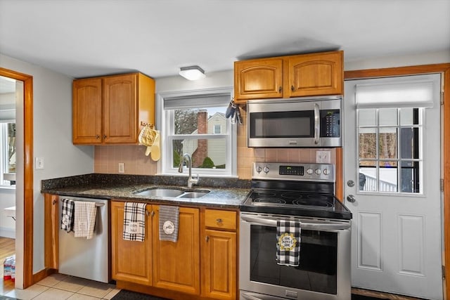 kitchen featuring appliances with stainless steel finishes, a sink, brown cabinetry, and tasteful backsplash