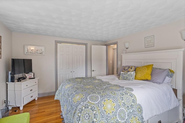 bedroom featuring light wood-style floors, a closet, and baseboards