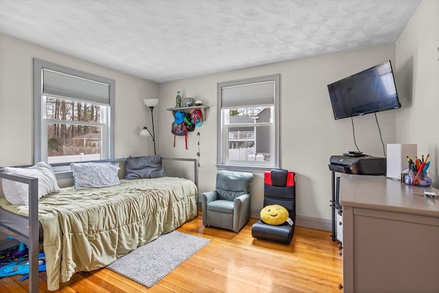 bedroom with multiple windows and light wood-type flooring
