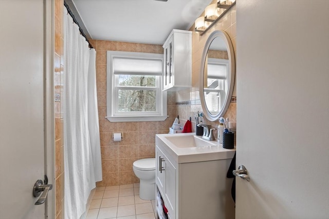bathroom with tile patterned flooring, tile walls, toilet, vanity, and curtained shower