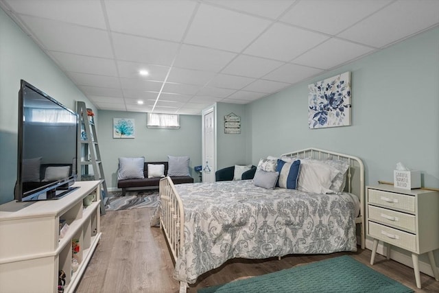 bedroom with a paneled ceiling, wood finished floors, and recessed lighting