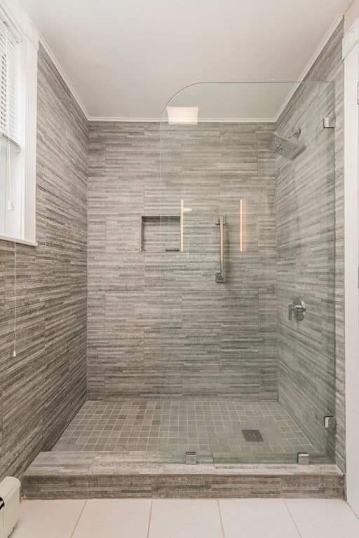 bathroom featuring tile patterned floors, a shower with door, and baseboard heating