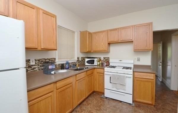 kitchen with light brown cabinets, white appliances, and sink