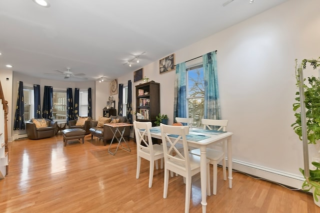 dining area with a wealth of natural light, light hardwood / wood-style flooring, ceiling fan, and a baseboard radiator