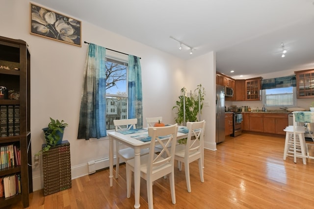 dining space with rail lighting, light hardwood / wood-style floors, and a wealth of natural light