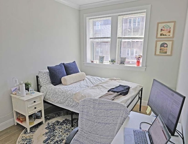 bedroom featuring baseboards, ornamental molding, and wood finished floors