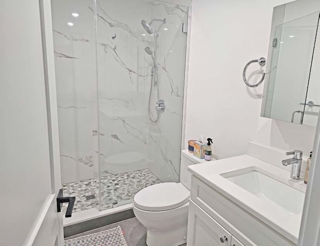 bathroom with toilet, a marble finish shower, and vanity