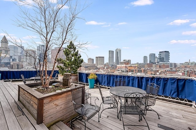 wooden terrace with a city view and outdoor dining area