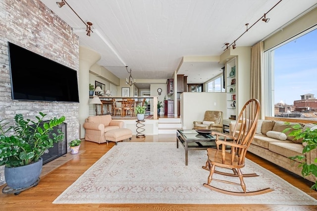 living area with rail lighting, wood finished floors, and a fireplace