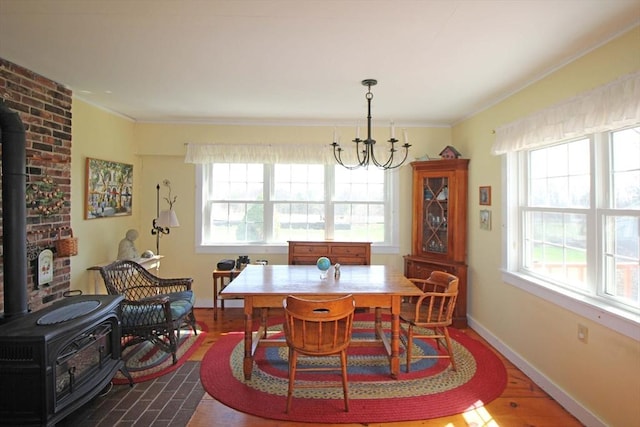 dining room with dark wood-type flooring, a chandelier, crown molding, and a wood stove