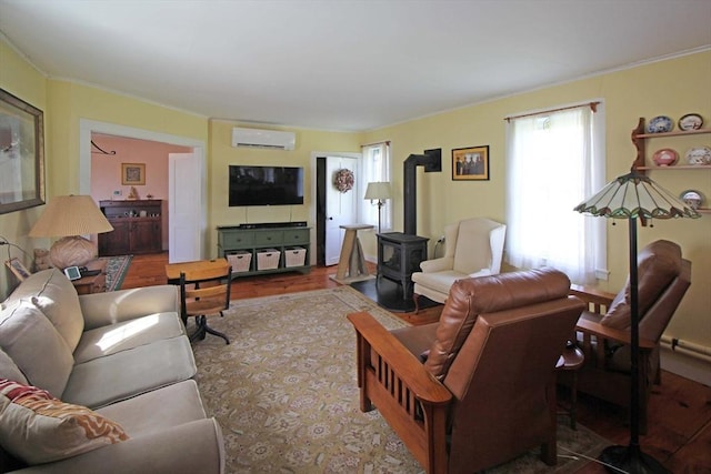 living area featuring a wood stove, wood finished floors, crown molding, and an AC wall unit