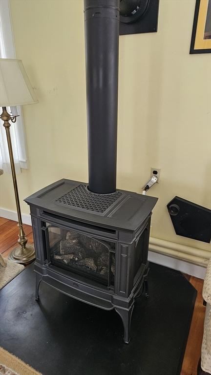 interior details featuring a wood stove, wood finished floors, and baseboards