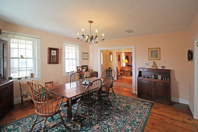 dining space featuring a textured ceiling, hardwood / wood-style floors, a chandelier, and visible vents