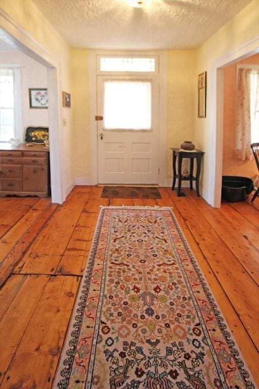 doorway to outside featuring a healthy amount of sunlight, a textured ceiling, and wood-type flooring