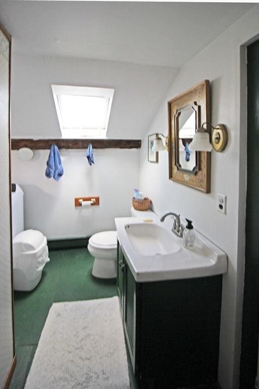 bathroom with vanity, toilet, and vaulted ceiling with skylight