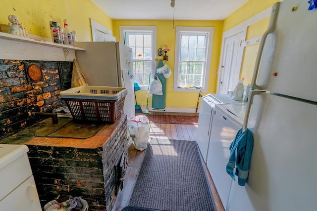 washroom with baseboards, laundry area, washer and clothes dryer, and wood finished floors
