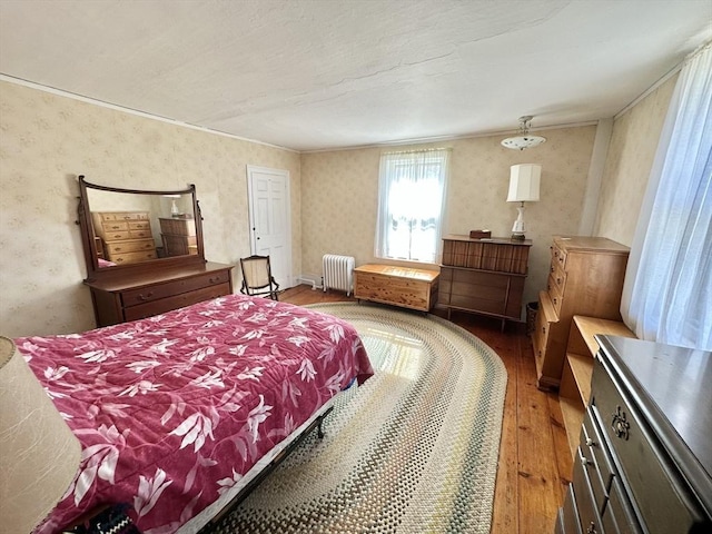 bedroom with ornamental molding, radiator heating unit, hardwood / wood-style flooring, and wallpapered walls