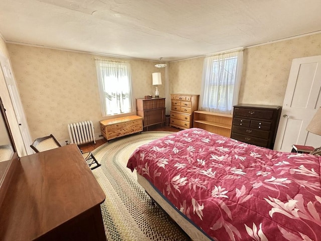 bedroom featuring wallpapered walls, ornamental molding, wood finished floors, and radiator