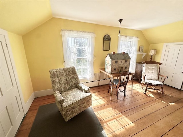 living area featuring wood-type flooring, vaulted ceiling, and baseboard heating