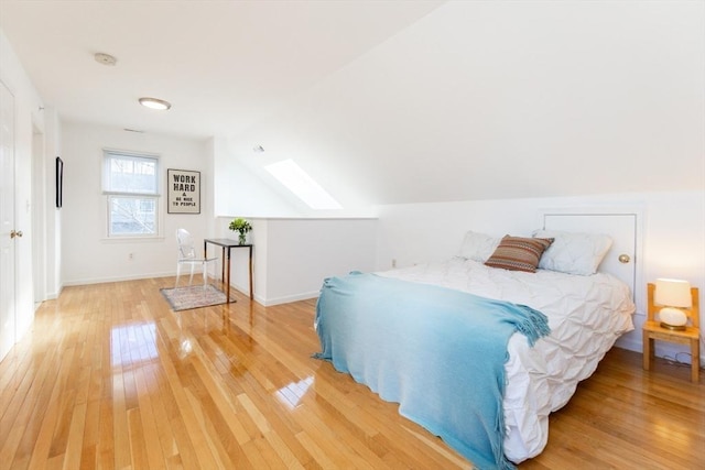 bedroom featuring light wood finished floors, baseboards, and lofted ceiling