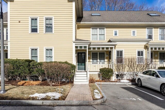 multi unit property featuring uncovered parking, a porch, and roof with shingles