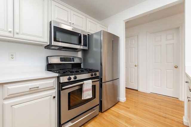 kitchen with white cabinetry, stainless steel appliances, light wood-type flooring, and light countertops