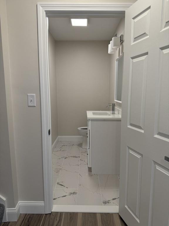 bathroom featuring toilet, baseboards, marble finish floor, and vanity