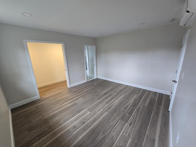 unfurnished bedroom featuring baseboards, a wall mounted air conditioner, recessed lighting, and wood finished floors