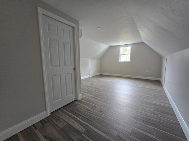 additional living space with vaulted ceiling, wood finished floors, and baseboards