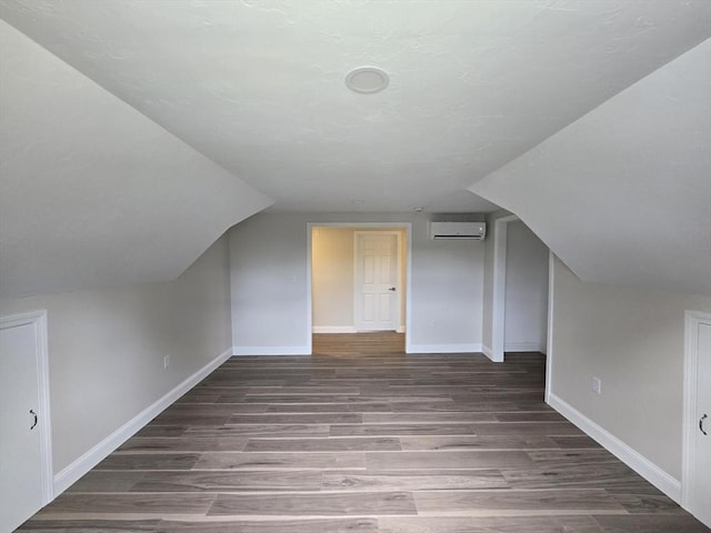 additional living space featuring baseboards, wood finished floors, lofted ceiling, and a wall mounted AC